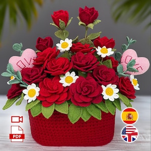 Puede incluir: Un arreglo floral rojo hecho a mano con ganchillo, en una cesta roja. El arreglo presenta rosas rojas, margaritas blancas y hojas verdes. También se incluyen corazones rosas de ganchillo con la palabra "LOVE". La cesta mide aproximadamente 15 cm de ancho.