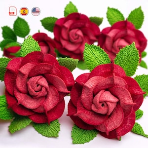 Puede incluir: Primer plano de varias rosas rojas hechas a mano con hojas verdes. Las rosas tienen un aspecto detallado y texturizado, con diferentes tonos de rojo. Las hojas verdes también están intrincadamente elaboradas, lo que se suma al aspecto realista del arreglo floral.