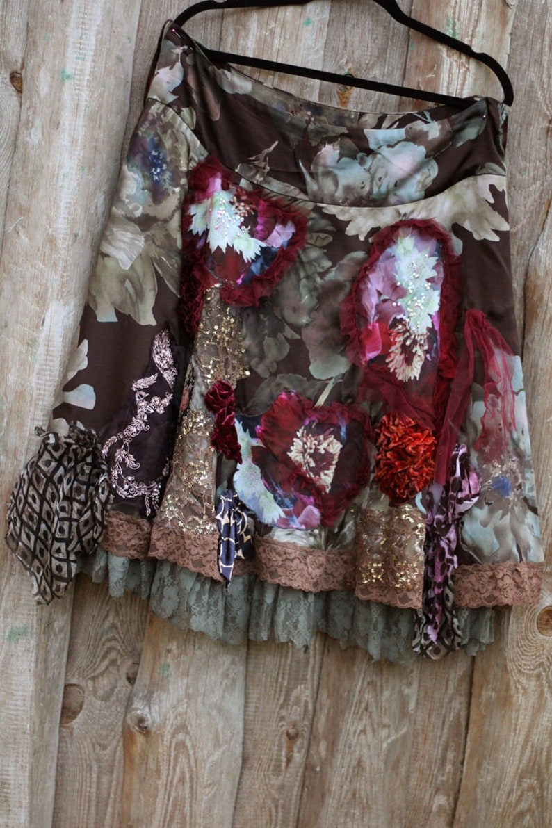 May include: A brown skirt with a floral print and layered lace trim. The skirt has a variety of embellishments, including sequins, beads, and fabric flowers.