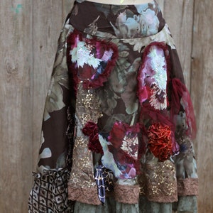 May include: A brown, floral skirt with a layered design. The skirt features a variety of fabrics, including lace, velvet, and chiffon. The skirt is decorated with sequins, beads, and flowers.
