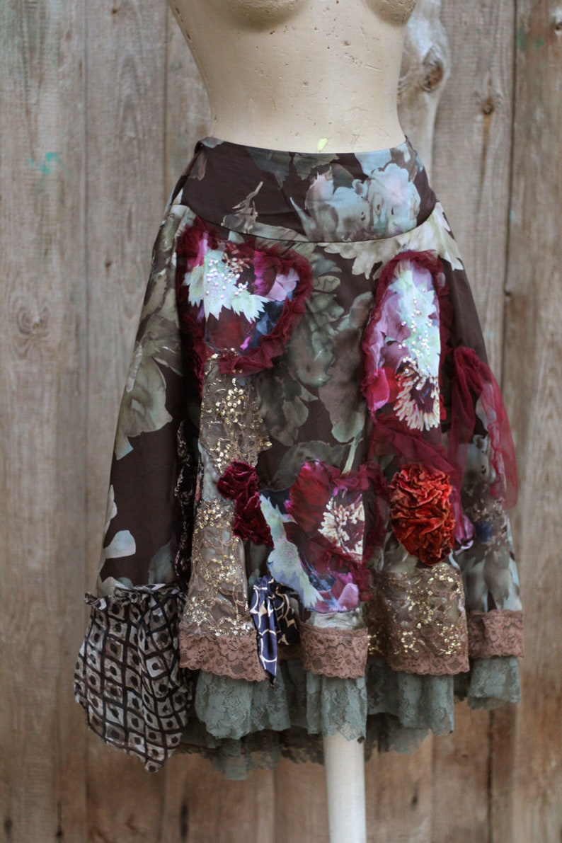 May include: A brown, floral skirt with a layered design. The skirt features a variety of fabrics, including lace, velvet, and chiffon. The skirt is decorated with sequins, beads, and flowers.