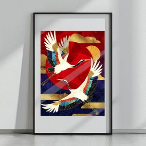 以下が含まれることがあります： 赤い太陽と青と金の背景を背景に、2羽の白い鶴が飛んでいる額入りのアートプリント。鶴はカラフルな翼のディテールを持っています。アートワークは黒いフレームに入っています。