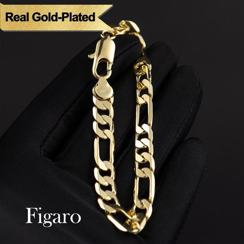 May include: A gold-plated Figaro chain bracelet. The bracelet features a classic curb link design with alternating long and short links. The clasp is a lobster claw style. The text "Real Gold-Plated" and "Figaro" are visible.