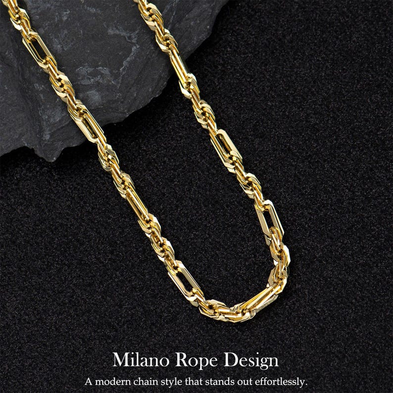 May include: A gold-colored chain necklace with a rope design. The chain is displayed on a dark, textured surface. The text "Milano Rope Design" and "A modern chain style that stands out effortlessly" is at the bottom.