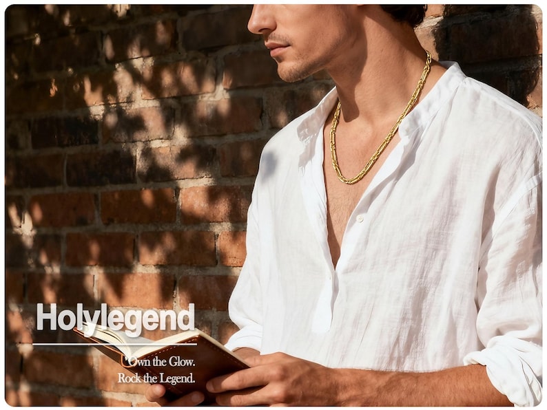 May include: A gold-colored necklace worn over a white linen shirt. The image shows a person holding a small brown book with the text "Holylegend" and the tagline "Own the Glow. Rock the Legend."