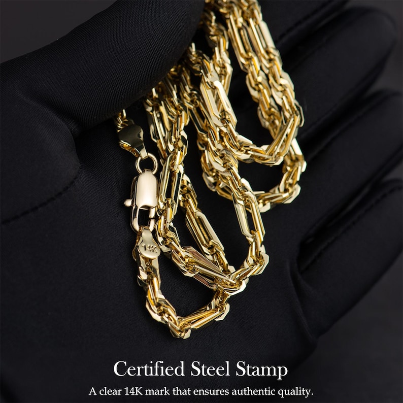 May include: A close-up of a gold chain necklace with a lobster clasp. The chain is made of interlocking rectangular links. The text "Certified Steel Stamp" and "A clear 14K mark that ensures authentic quality" are at the bottom of the image.