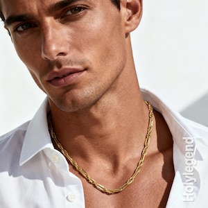 May include: A gold-colored chain necklace with a rectangular link design. The necklace is worn over a white button-down shirt. The image is well-lit, highlighting the necklace's details and the shirt's texture.