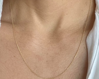 May include: A delicate gold chain necklace on a person's neck.