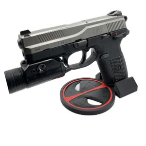 May include: A black and silver handgun with a black tactical light attached to the barrel. The gun is resting on a black stand with a red Deadpool logo.