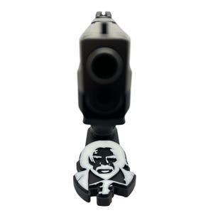 May include: A black toy gun with a white silhouette of a man's face on the bottom. The man has a mustache and a goatee.