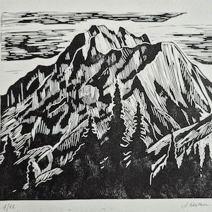Pode incluir: Gravura em linóleo a preto e branco retratando uma paisagem montanhosa. A obra apresenta uma representação detalhada de uma cordilheira, árvores e nuvens, com a assinatura do artista e o número da edição.