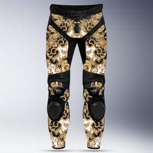 May include: Black and gold motorcycle pants with a baroque pattern. The pants feature a black leather belt, knee pads, and a white background with a gold floral design. The pants are designed for motorcycle riding.