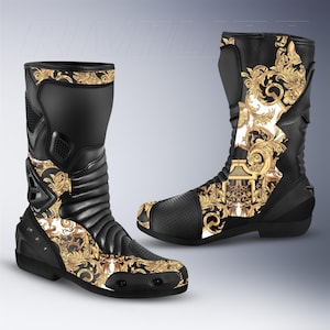 Könnte beinhalten: Paar schwarze Motorradstiefel mit goldenen Barockdetails. Die Stiefel haben ein schlankes Design mit verstärkten Einsätzen und einem strukturierten Zehenbereich. Das goldene Muster ist auf der Vorder- und Seite zu sehen.