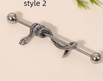 May include: A silver industrial barbell piercing featuring a detailed snake design coiled around the bar. The barbell has a ball at each end. The text "style 2" is in the upper left corner.