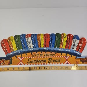 May include: Vintage Sunbeam Bread sign with a colourful Native American headdress design. The sign has the text "LET'S BE FRIENDS" and "Sunbeam Bread". The sign is approximately 40 cm long.