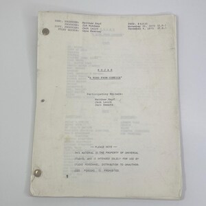 May include: A vintage script titled "KOJAK" with the episode name "A Wind From Corsica." The document is on aged paper, secured with brass fasteners. The text includes production details, writer credits, and a copyright notice.