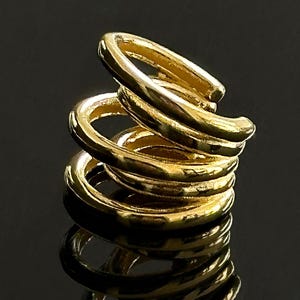 Könnte beinhalten: Goldfarbener Spiral-Ohrring aus mehreren übereinanderliegenden Ringen. Die Ringe sind strukturiert und haben eine gehämmerte Oberfläche.