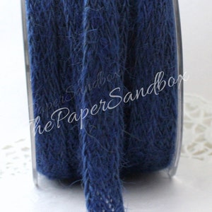 May include: A spool of navy blue jute ribbon. The ribbon is tightly woven and has a slightly textured appearance. The spool is partially visible, and the ribbon is unrolled, showing its thickness and color. The Paper Sandbox is printed on the image.