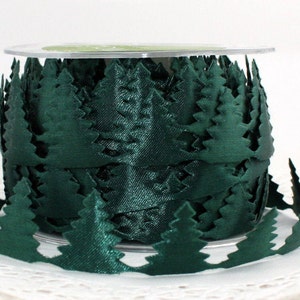 May include: A spool of dark green satin ribbon with a forest edge design. The ribbon is a deep forest green color, with the edges cut out in the shape of evergreen trees. The ribbon is on a clear plastic spool.