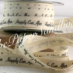 May include: Cream-colored ribbon spools with the words "Happily Ever After" printed in black. The ribbon is unspooled, revealing the text and texture of the fabric. Ideal for wedding crafts and decorations.