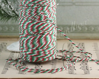 May include: A spool of red, white, and green baker's twine. The twine is tightly wound around a wooden core, with strands extending outwards. The colors are arranged in a twisted pattern, creating a festive look. The twine is suitable for crafts and gift wrapping.