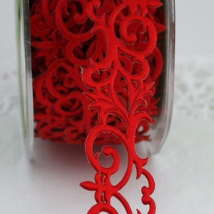 May include: A spool of red decorative ribbon with a repeating floral scroll design. The ribbon is made of a soft fabric and is ideal for crafts, gift wrapping, or embellishing various projects. The ribbon is on a clear plastic spool.