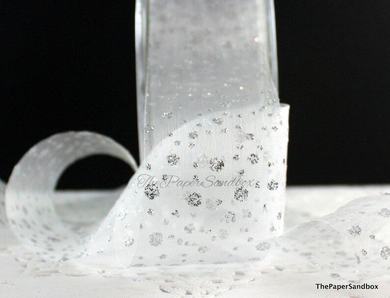 May include: White sheer ribbon with silver glitter detailing. The ribbon is rolled and curled, displaying a delicate, dotted design. The Paper Sandbox logo is visible in the lower right corner.