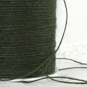 May include: A spool of dark green twine. The twine is tightly wound, with a visible texture from the individual fibers. A length of the twine extends from the spool, creating a curved line against a white background. Ideal for crafts and packaging.