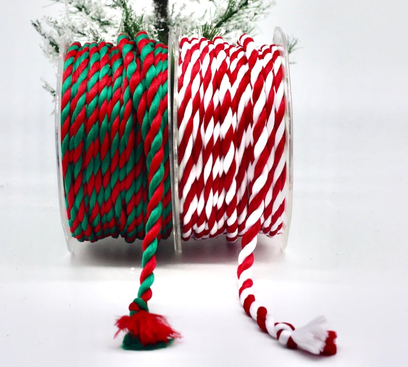 May include: Two spools of decorative rope. One spool features red and green twisted rope, and the other has red and white twisted rope. The rope is wound on clear plastic spools, perfect for holiday crafts and gift wrapping.