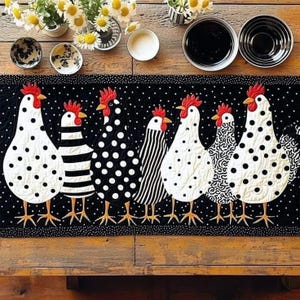 May include: A black and white quilted table runner featuring six stylized chickens with various patterns. The chickens have red combs and yellow beaks. The runner is decorated with a polka dot border and is placed on a wooden table.