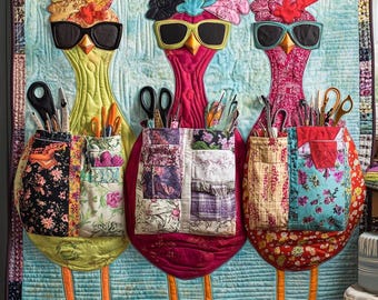 May include: A colorful, quilted wall hanging featuring three whimsical chicken figures wearing sunglasses and elaborate headpieces. Each chicken has a patchwork pocket filled with craft supplies. The background is a light blue with a quilted texture.