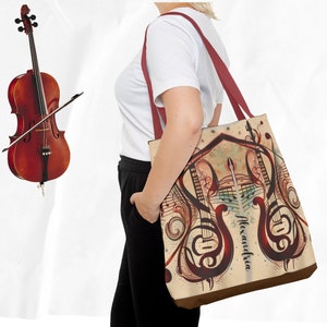 May include: A beige tote bag with a brown leather bottom. The bag features a colorful design of two stylized guitars with musical notes and swirls. The name "Alexandria" is written in cursive on the bag.