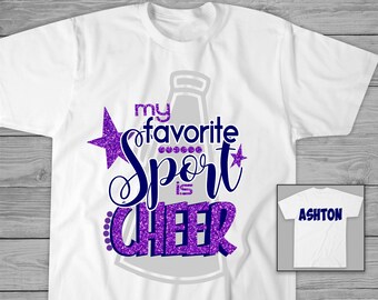 May include: White t-shirt with purple glitter text that says "My favourite sport is cheer" with a cheerleading megaphone graphic. The text is in a blue font. A white t-shirt with the name "Ashton" is in the background.