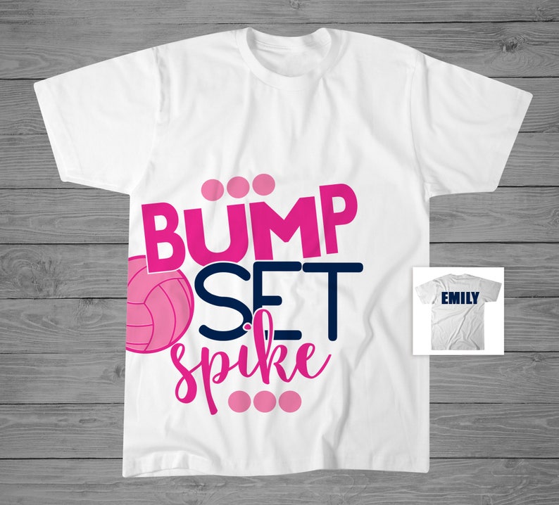 May include: White t-shirt with the words "Bump Set Spike" in pink and blue lettering. A pink volleyball is to the left of the text. The text "Emily" is on a white t-shirt in the background.