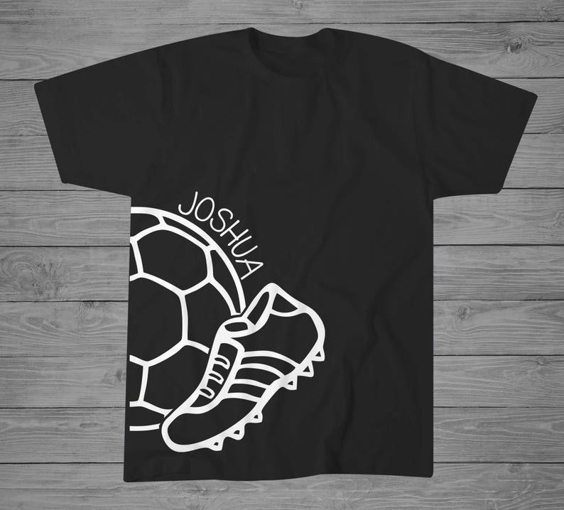 May include: Black t-shirt with a white outline of a soccer ball and a soccer cleat. The text "JOSHUA" is written on the shirt.