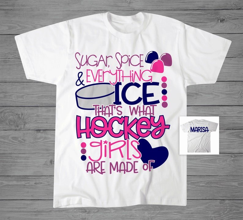 May include: White t-shirt with pink and blue text that reads "Sugar, Spice & Everything Nice: That's What Hockey Girls Are Made Of". The text is surrounded by pink and blue hearts and a hockey puck. The shirt is personalised with the name "MARISA" on a white t-shirt.
