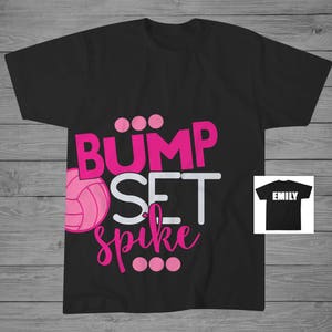 May include: Black t-shirt with the text "Bump Set Spike" in pink and white letters. A pink volleyball is included in the design. The text "Emily" is on a separate black t-shirt.