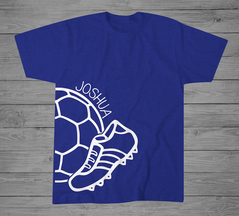 May include: A royal blue t-shirt with a white outline of a soccer ball and a soccer cleat. The name "Joshua" is written on the shirt.