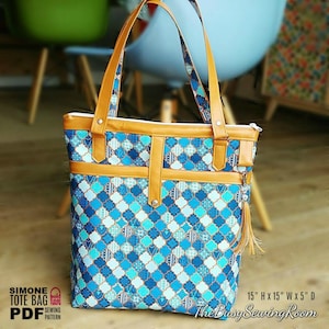 Puede incluir: Una bolsa de mano azul y blanca con estampado, con asas y ribetes de cuero marrón. La bolsa tiene cierre de cremallera y un pequeño bolsillo en la parte delantera. La bolsa mide 38 cm de alto, 38 cm de ancho y 13 cm de profundidad.