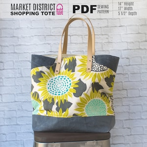 May include: A large tote bag with a sunflower print. The bag is made of canvas and has leather handles. The bag is 14 inches high, 17 inches wide, and 5 1/2 inches deep.