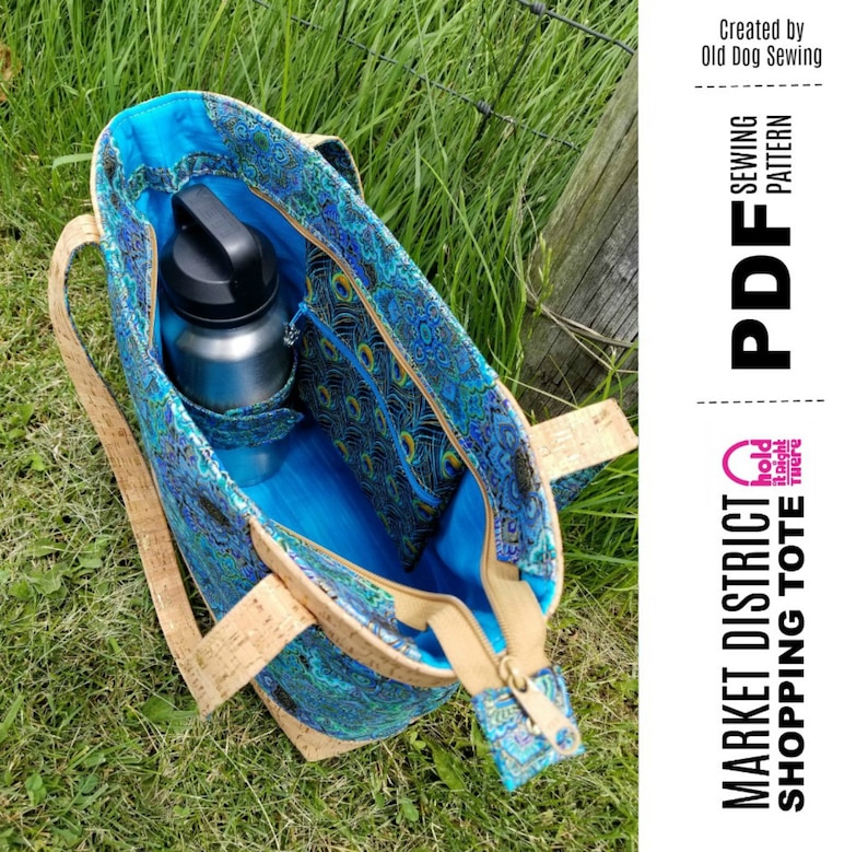 May include: A blue and brown tote bag with a zipper closure and a cork fabric exterior. The bag has a large interior pocket and a smaller pocket on the outside. The bag is open and a silver water bottle is inside. The text "MARKET DISTRICT SHOPPING TOTE" and "PDF SEWING PATTERN" is on the right side of the image.