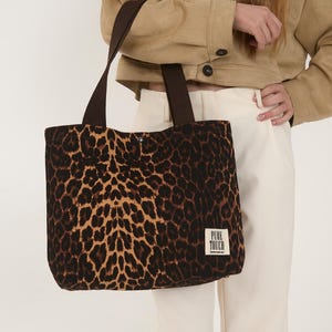 Op de afbeelding: Een bruine en beige tote bag met luipaardprint, met bruine hengsels en een klein wit label met de tekst "PURE TOUCH".