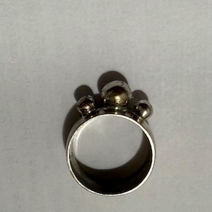Peut inclure: Une bague en argent avec trois boules rondes en argent sur le dessus.