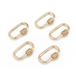 May include: Five gold-colored oval carabiner clasps with a sparkling, textured cylinder at the center. The clasps are arranged on a white background. These jewelry findings are suitable for necklaces, bracelets, and other craft projects.