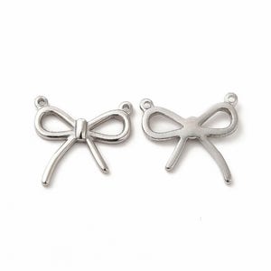 May include: Two silver metal bow charms with a loop at the top for attaching to jewelry or other crafts.