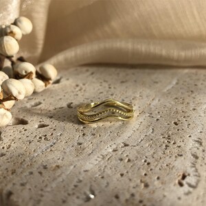 May include: Gold-toned ring with a wavy design. The ring is made of three bands that are intertwined.