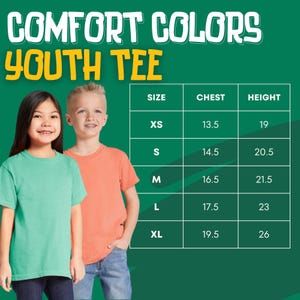 Puede incluir: Dos ni&ntilde;os con camisetas Comfort Colors Youth. Una tabla de tallas muestra medidas de pecho en cm: XS (34,3), S (36,8), M (41,9), L (44,5), XL (49,5). Las alturas son: XS (48,3), S (52,1), M (54,6), L (58,4), XL (66). El texto "COMFORT COLORS YOUTH TEE" est&aacute; en la parte superior.