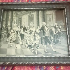 Pode incluir: Impressão emoldurada em preto e branco retratando uma cena de salão de baile com figuras em trajes de época dançando e músicos tocando. A moldura ornamentada tem uma borda prateada. A obra de arte evoca uma sensação de elegância histórica e arte clássica.