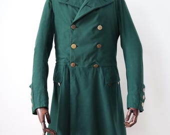 May include: A dark green double-breasted coat with gold-colored buttons. The coat has a tailored fit, long sleeves, and a notched collar. The coat is displayed on a mannequin.