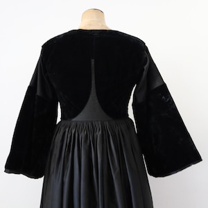 May include: A black velvet and satin dress with long sleeves and a gathered skirt.